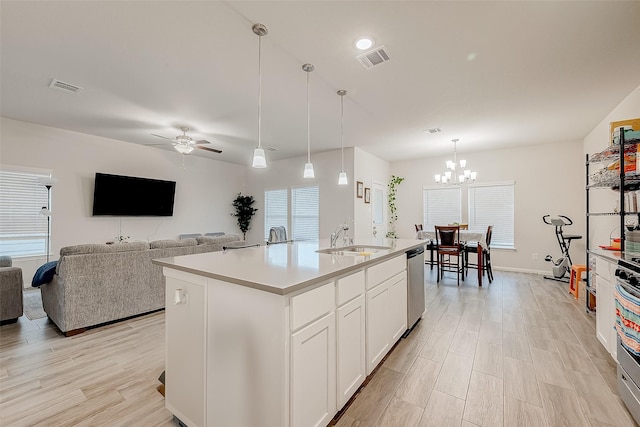 kitchen with stainless steel appliances, a kitchen island with sink, hanging light fixtures, ceiling fan with notable chandelier, and sink