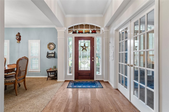 entrance foyer with crown molding, wood-type flooring, french doors, and ornate columns