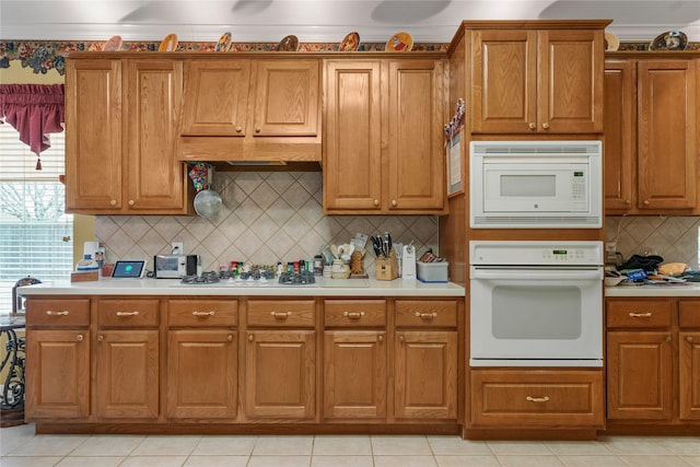 kitchen with tasteful backsplash, ornamental molding, light tile patterned floors, and white appliances