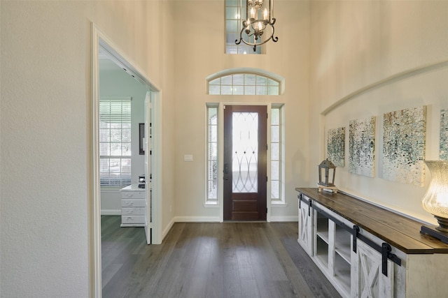 entrance foyer with baseboards, a notable chandelier, a high ceiling, and dark wood-style flooring