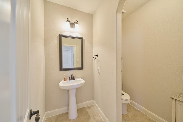 bathroom with tile patterned floors, toilet, and baseboards