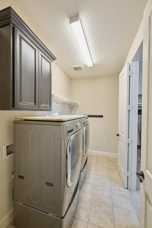 laundry room with visible vents, independent washer and dryer, a textured ceiling, cabinet space, and light tile patterned flooring