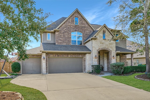 french provincial home featuring concrete driveway, stone siding, brick siding, and roof with shingles