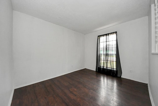 unfurnished room with a textured ceiling and dark hardwood / wood-style flooring