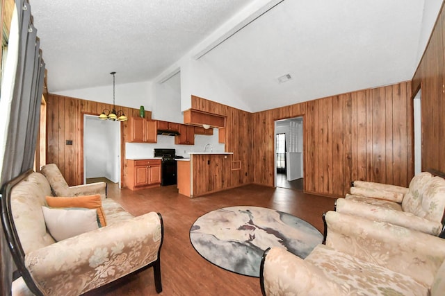 living room with a textured ceiling, wooden walls, lofted ceiling with beams, and an inviting chandelier