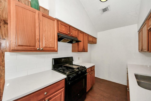 kitchen with sink, black gas range oven, dark hardwood / wood-style flooring, and vaulted ceiling