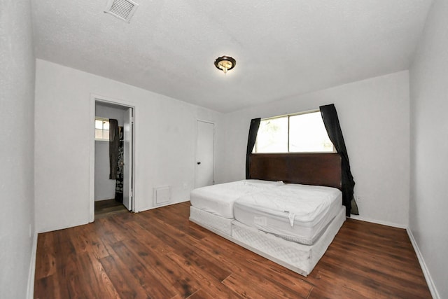 bedroom featuring a textured ceiling, dark hardwood / wood-style floors, and ensuite bath