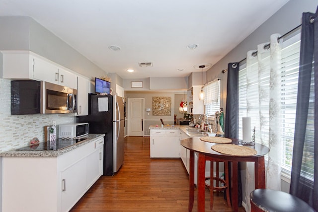 kitchen featuring white cabinetry, decorative light fixtures, sink, backsplash, and appliances with stainless steel finishes