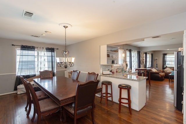 dining area with a healthy amount of sunlight, an inviting chandelier, and dark hardwood / wood-style flooring