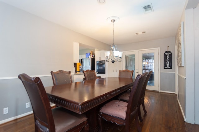 dining space with dark hardwood / wood-style flooring, french doors, and an inviting chandelier