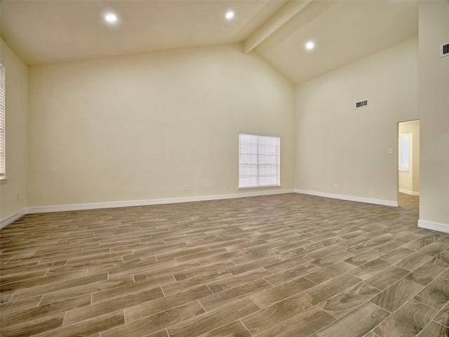 unfurnished room with beam ceiling and high vaulted ceiling