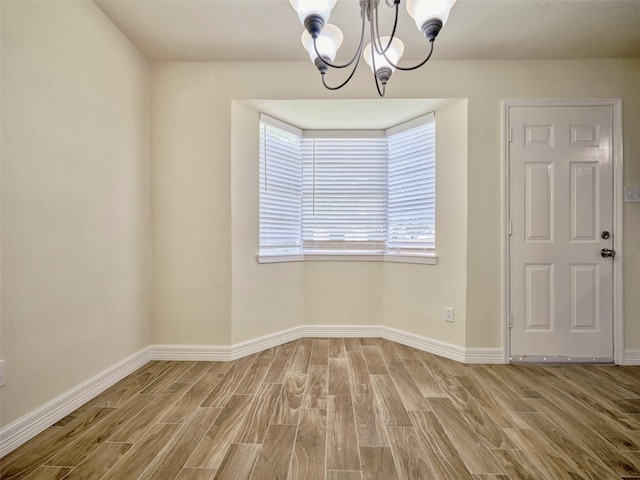 empty room with wood-type flooring and a chandelier