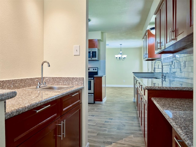 kitchen with hanging light fixtures, appliances with stainless steel finishes, sink, and stone counters