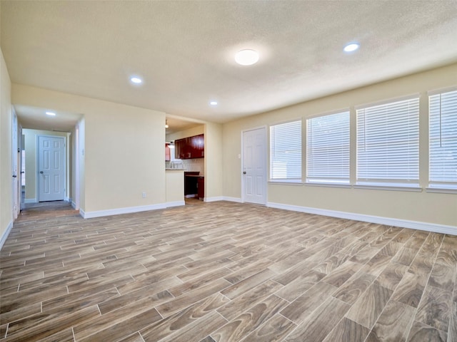 unfurnished living room with a textured ceiling and light hardwood / wood-style flooring