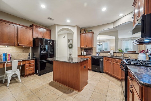 kitchen featuring dark stone counters, a center island, tasteful backsplash, and black appliances