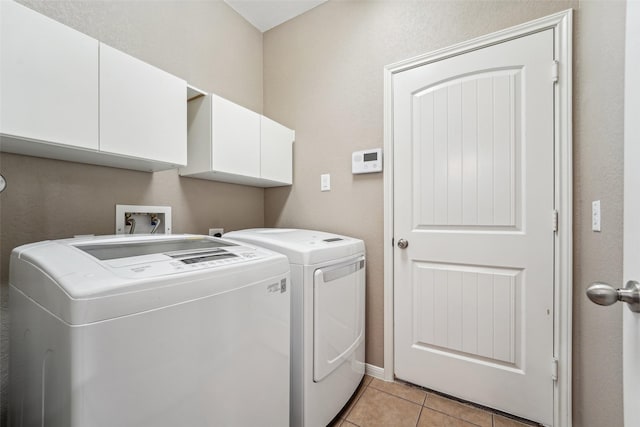 washroom with light tile patterned floors, cabinets, and washer and clothes dryer