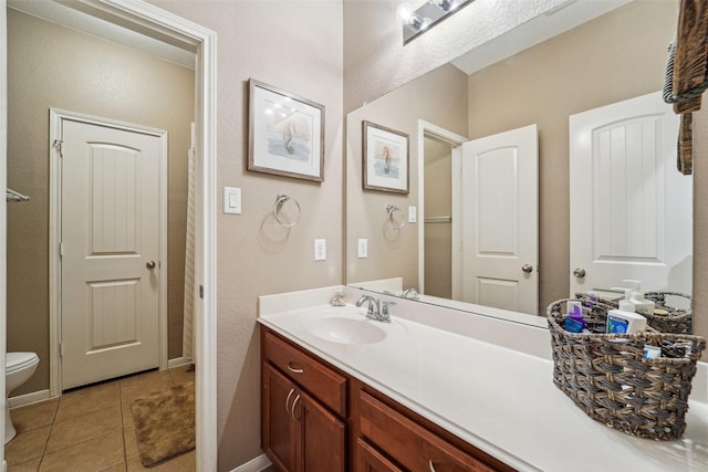 bathroom with toilet, vanity, and tile patterned flooring