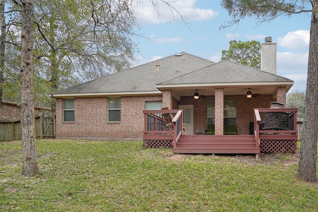 rear view of property with ceiling fan, a wooden deck, and a yard