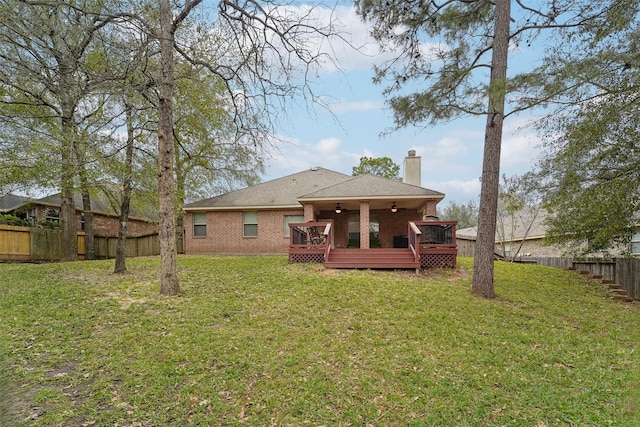 back of property featuring ceiling fan, a deck, and a yard