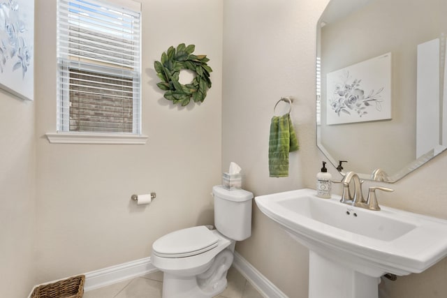 bathroom with toilet, sink, and tile patterned floors