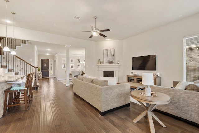 living room with ornate columns, dark hardwood / wood-style flooring, and ceiling fan with notable chandelier