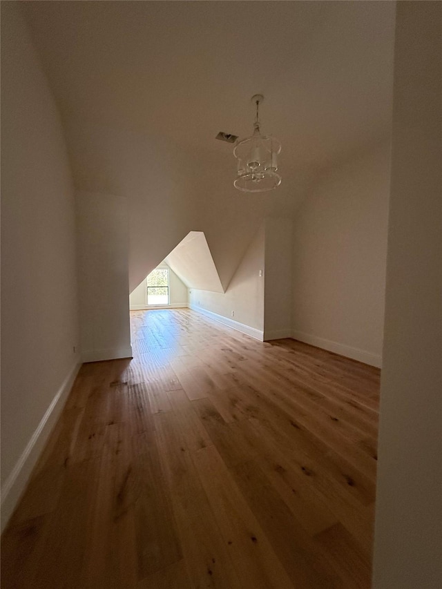 bonus room featuring vaulted ceiling, a notable chandelier, and hardwood / wood-style flooring