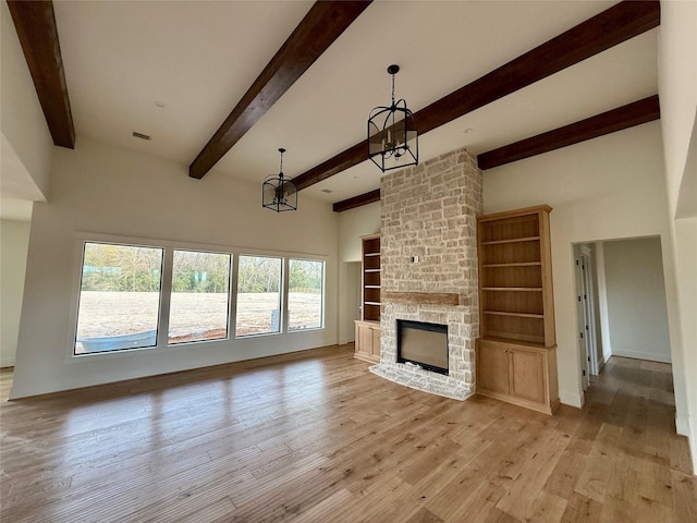 unfurnished living room featuring a chandelier, light wood-type flooring, beamed ceiling, and a fireplace