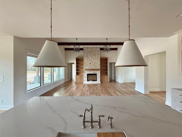 living room featuring a large fireplace, light hardwood / wood-style flooring, and beamed ceiling