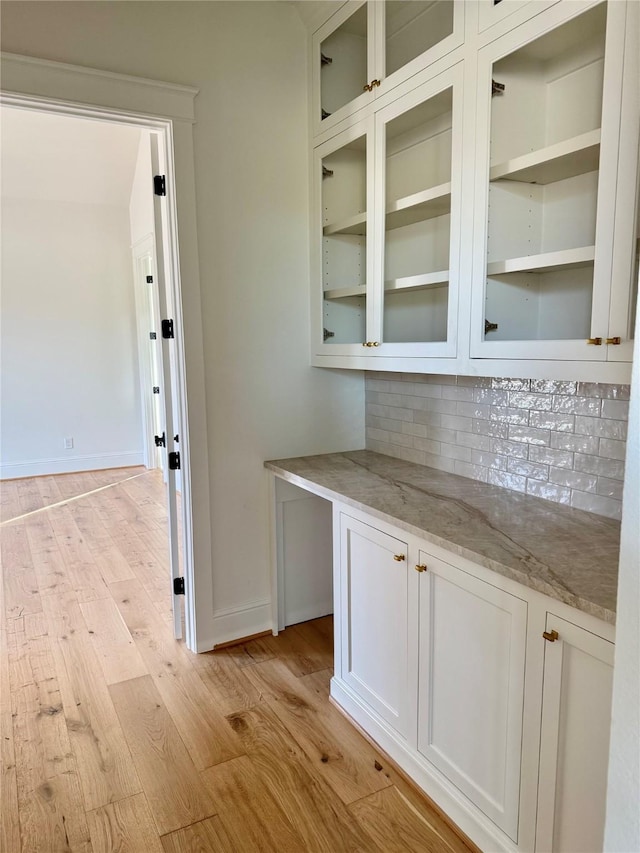 bar featuring white cabinetry, light hardwood / wood-style floors, light stone counters, and backsplash