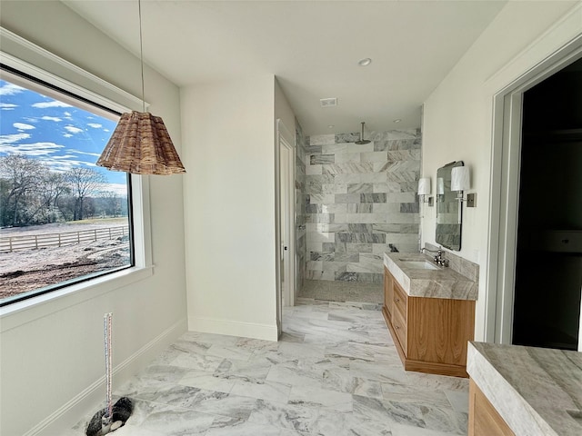 bathroom featuring tiled shower and vanity