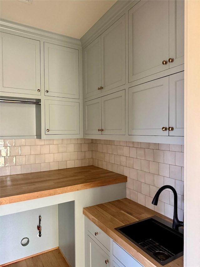 kitchen with decorative backsplash, sink, butcher block countertops, and light hardwood / wood-style floors