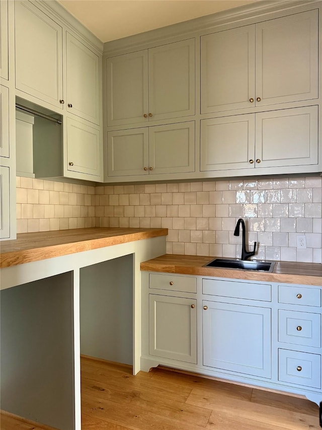 kitchen featuring sink, backsplash, wood counters, and light hardwood / wood-style floors