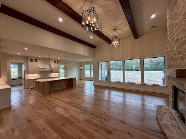 kitchen featuring pendant lighting, a spacious island, a fireplace, wood-type flooring, and decorative backsplash