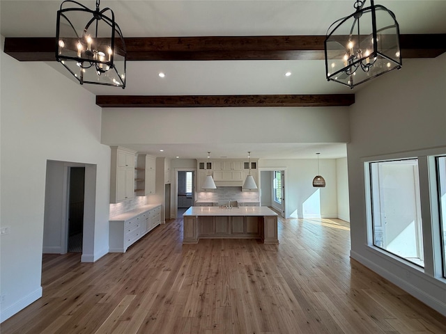 kitchen featuring pendant lighting, a large island, light hardwood / wood-style floors, decorative backsplash, and white cabinets