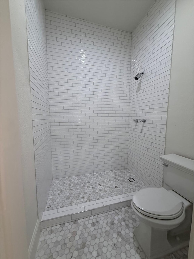 bathroom featuring tile patterned flooring, tiled shower, and toilet