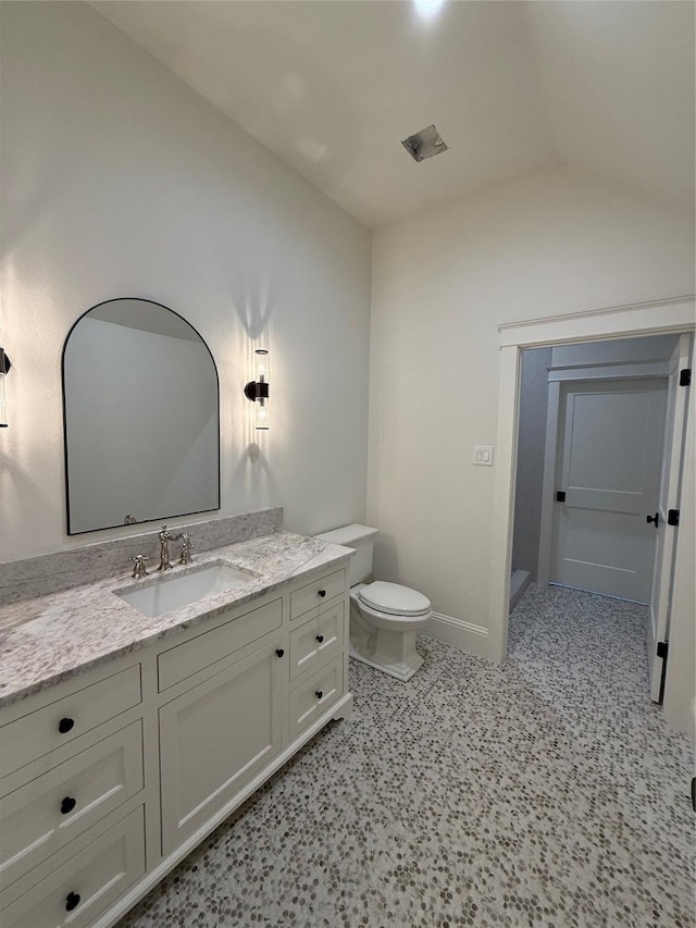 bathroom with lofted ceiling, vanity, and toilet