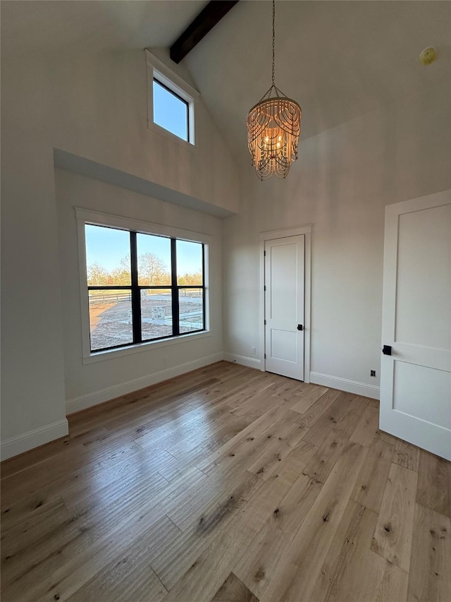 interior space with beam ceiling, a chandelier, high vaulted ceiling, and light hardwood / wood-style flooring