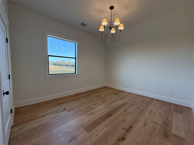 empty room with vaulted ceiling, light hardwood / wood-style flooring, and a notable chandelier