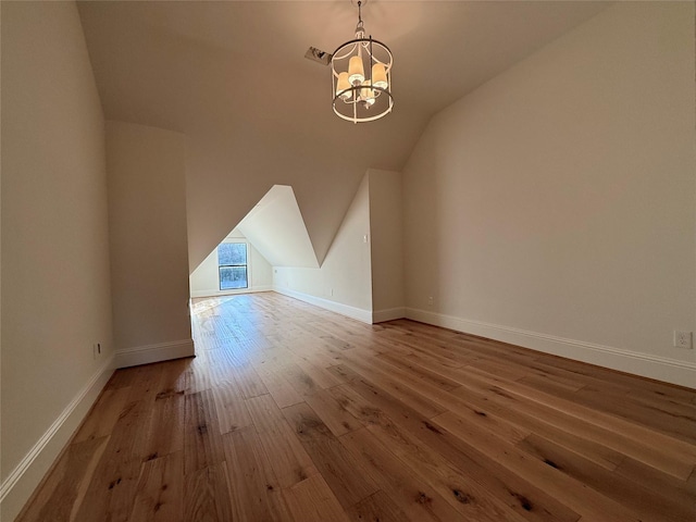 additional living space with lofted ceiling, wood-type flooring, and a notable chandelier