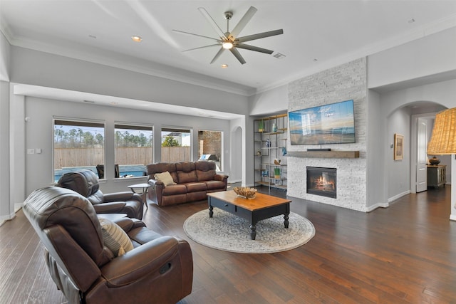 living room featuring ornamental molding, dark wood-type flooring, a fireplace, and built in shelves