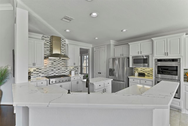 kitchen featuring tasteful backsplash, wall chimney exhaust hood, stainless steel appliances, and light stone countertops