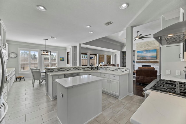 kitchen with sink, white cabinetry, kitchen peninsula, a kitchen island, and pendant lighting