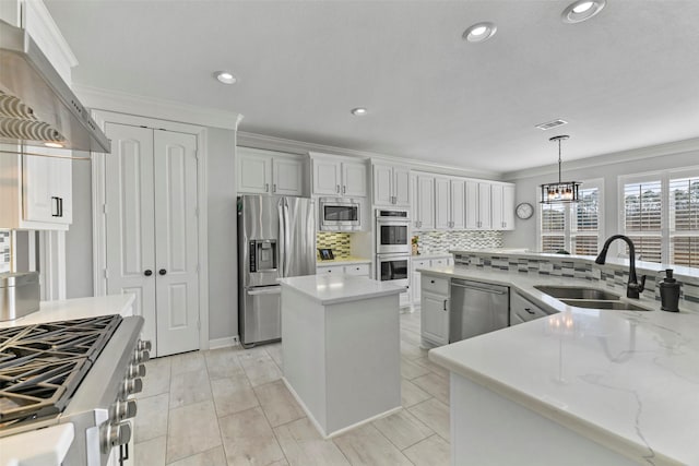 kitchen with decorative light fixtures, sink, a center island, stainless steel appliances, and wall chimney range hood