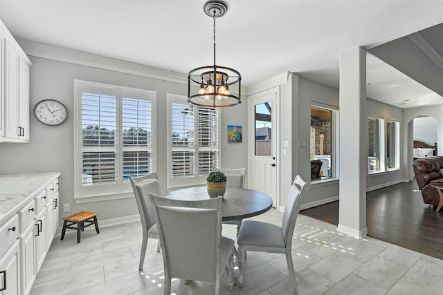 tiled dining space featuring an inviting chandelier, crown molding, and a healthy amount of sunlight