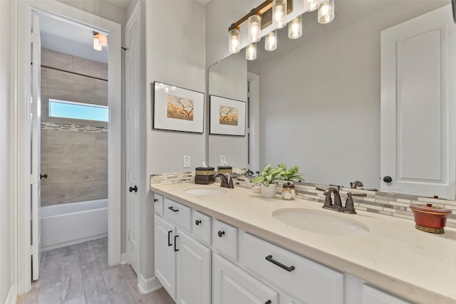 bathroom featuring hardwood / wood-style flooring, vanity, tiled shower / bath combo, and decorative backsplash