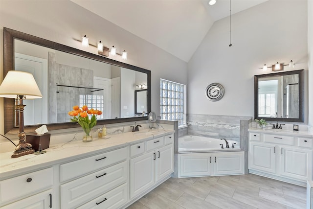 bathroom featuring independent shower and bath, vaulted ceiling, a wealth of natural light, and vanity