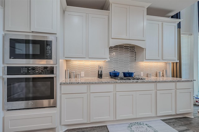 kitchen featuring stainless steel appliances, white cabinets, and light stone countertops