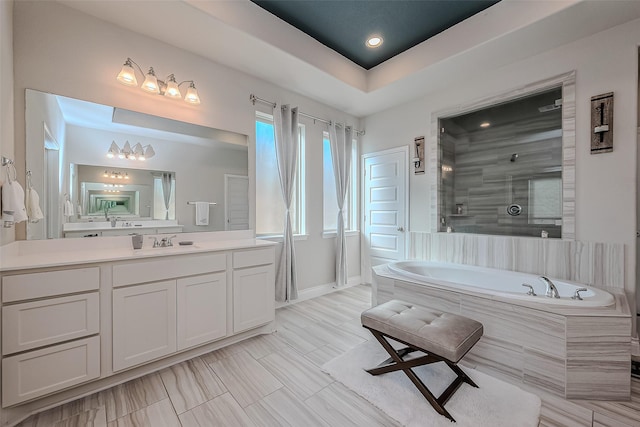 bathroom with a tray ceiling, vanity, and shower with separate bathtub