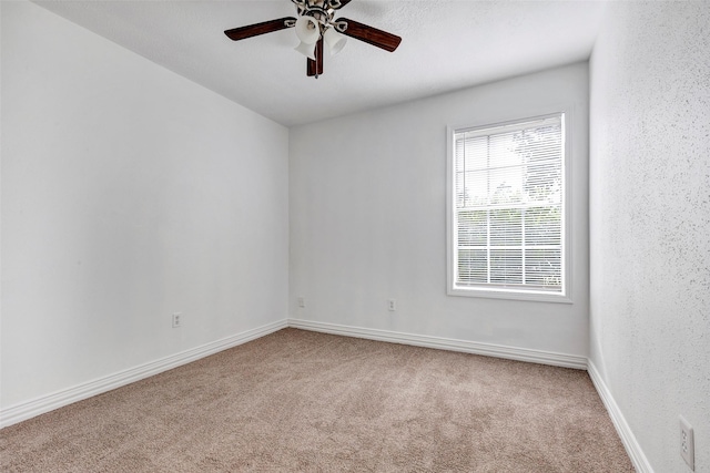 unfurnished room with ceiling fan and carpet