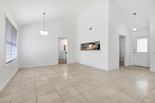 unfurnished living room featuring high vaulted ceiling and light tile patterned floors